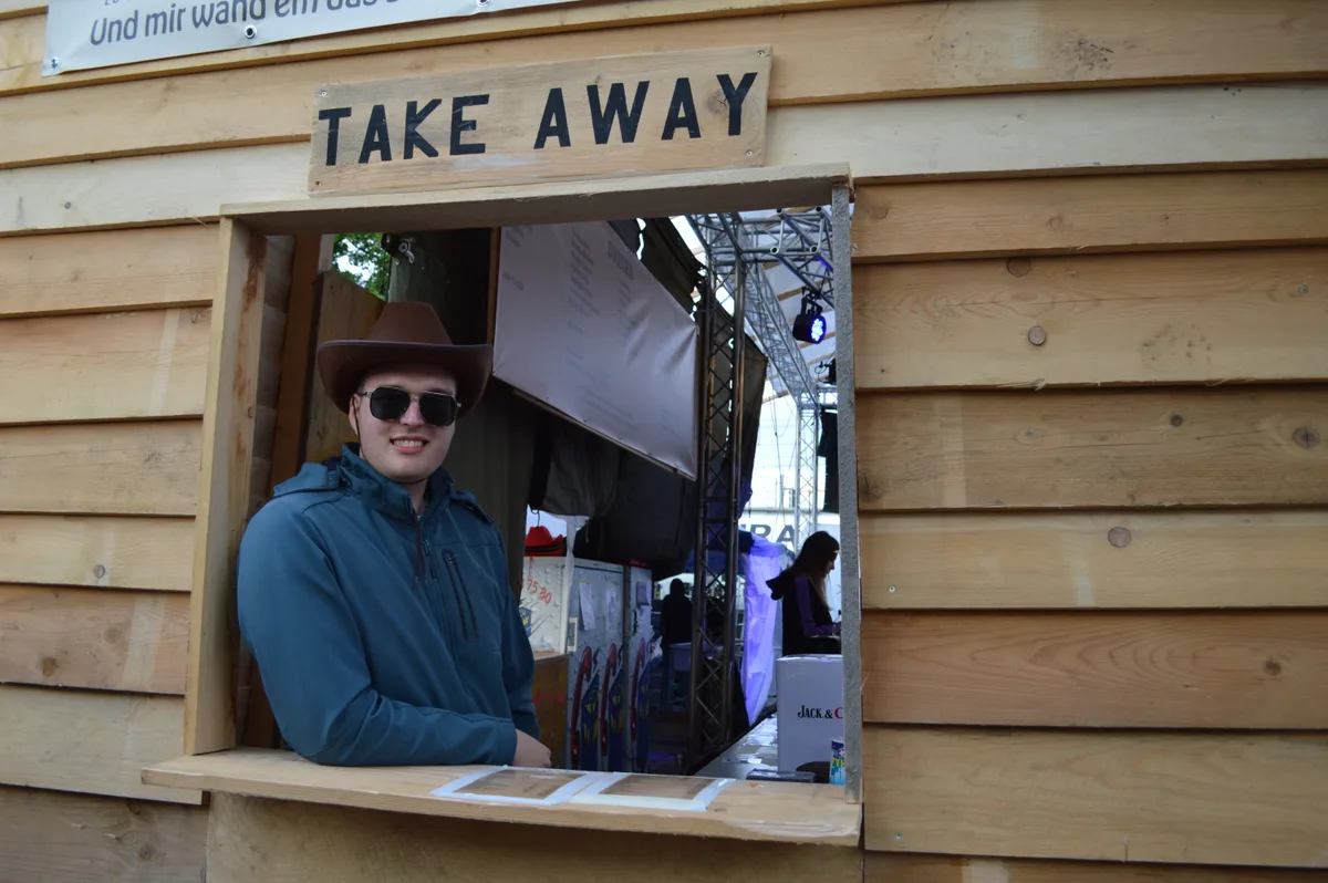 Ein Mann mit Cowboyhut schaut aus einem Saloon-Fenster.